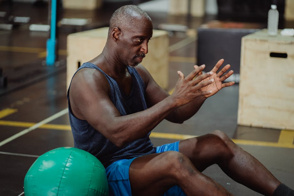 Focused man in gym performing exercises with a fitness ball, showcasing fitness and determination.