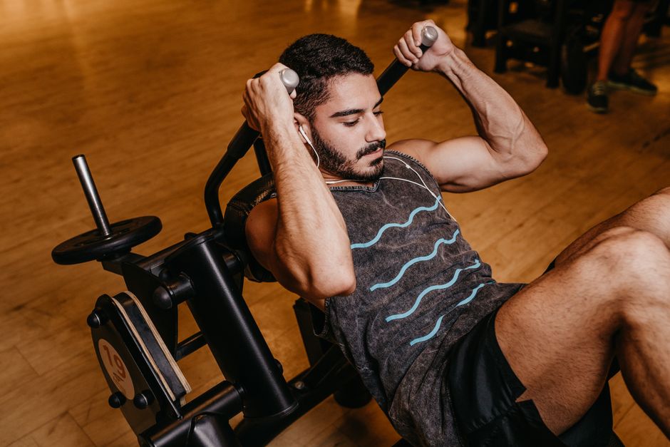 An adult man working out indoors on gym equipment, building muscle and strength.